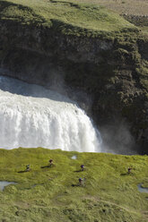 Island, Männer beim Mountainbiking neben einem Wasserfall - FF00983