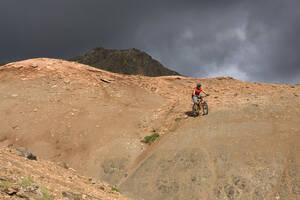 Island, Mann beim Mountainbiking in hügeliger Landschaft - FF00979