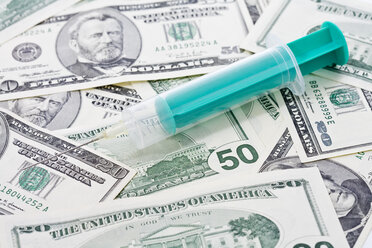 US Dollar bills, Syringe placed on top, close up - MAEF01370