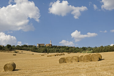 Italien, Toskana, Strohballen auf einem Feld, Pienza im Hintergrund - FOF01255