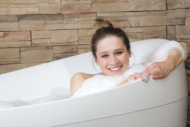 Young woman in bathtub, smiling, portrait - NHF01078