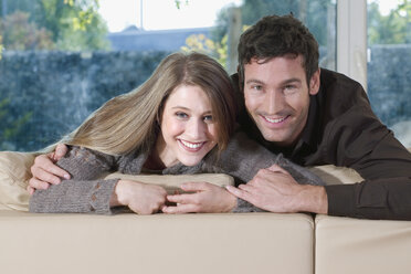 Junges Paar auf Sofa, lächelnd, Porträt - NHF01060