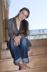 Junge Frau auf einer Treppe sitzend, lächelnd, Porträt - NHF01055