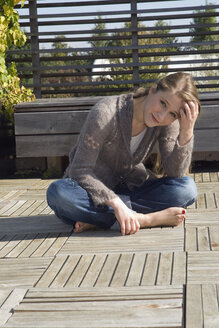Junge Frau auf Terrasse sitzend, Porträt - NHF01053