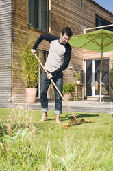 Junger Mann beim Laubharken im Garten - NHF01044