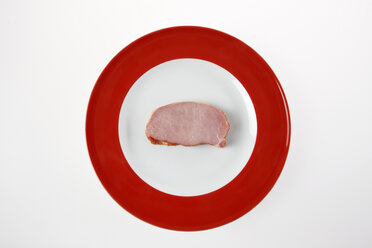 Raw pork chop on plate, elevated view - KSWF00301