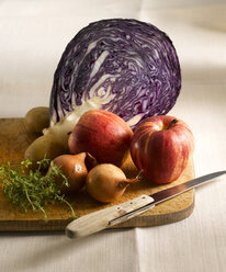 Red cabbage, apples, potatoes, thyme and onions on chopping board - KSWF00252