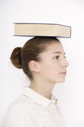 Junge Frau (16-17), die ein Buch auf dem Kopf balanciert - TCF01174