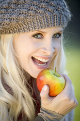 Junge Frau mit Apfel in der Hand, lächelnd, Porträt, Close-uo - MAEF01465