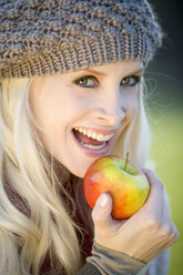 Young woman holding an apple, smiling, portrait, close-uo - MAEF01465