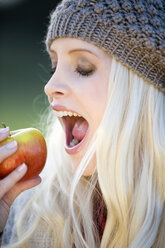 Junge Frau beißt in einen Apfel, Porträt - MAEF01464