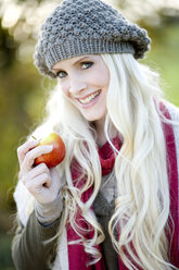 Young woman holding an apple, smiling, portrait - MAEF01463