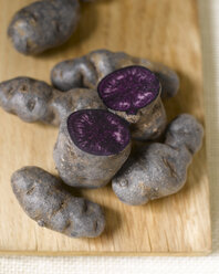 Truffle de Chine blue-violet potatoes on chopping board, elevated view - KSW00347