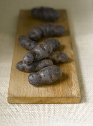 Truffle de Chine blue-violet potatoes on chopping board - KSW00346