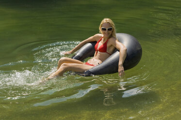 Österreich, Salzburger Land, Reitecksee, Junge Frau entspannt auf schwimmendem Reifen - HHF02783