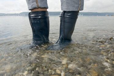 Germany, Baden-Württemberg, Lake Constance, Person in boots standing in water, low section - SHF00279