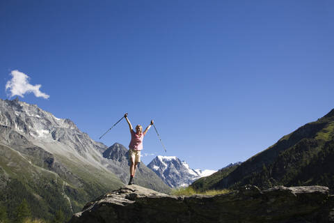 Schweiz, Walliser Alpen, Mont Collon, Frau mit Wanderstöcken, jubelnd, lizenzfreies Stockfoto