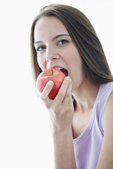 Junge Frau beißt in einen Apfel, Porträt, Nahaufnahme - WESTF10928