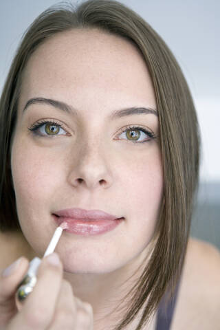 Junge Frau benutzt einen Lippenstift, Porträt, Nahaufnahme, lizenzfreies Stockfoto