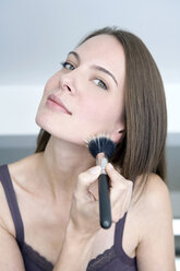 Young woman using make-up brush, portrait, close up - WESTF10910