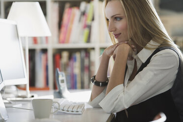 Young woman in office sitting at computer - WESTF10685