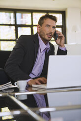 Business man in office using mobile phone, portrait - WESTF10671