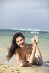 Young woman lying on beach, smiling, portrait - ABF00514