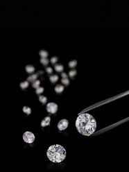 Tweezers and cut diamonds against black background - AKF00050