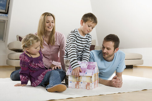 Family relaxing at home,Boy building house from Euro notes - CLF00677
