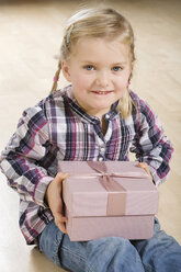 Little girl (3-4) holding gift parcel, smiling - CLF00663