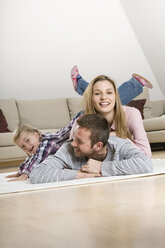 Parents and daughter (3-4) at home, lying on floor, fooling about - CLF00652