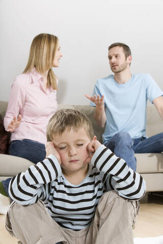 Eltern streiten sich, Junge (4-5) sitzt im Vordergrund, lizenzfreies Stockfoto