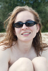 Young woman on beach wearing sunglasses, smiling, portrait - MUF00763