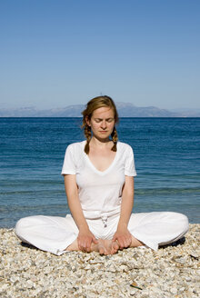 Greece, Ithaca, Woman exercising yoga on beach - MUF00761