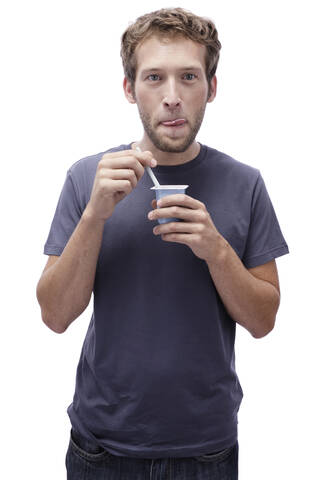 Young man holding yoghurt, portrait stock photo