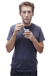 Young man holding yoghurt, portrait - BMF00550
