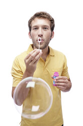 Young man blowing soap bubbles, portrait - BMF00538