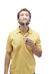 Young man holding yoghurt, balancing spoon on nose, portrait - BMF00536
