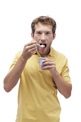 Young man eating Yoghurt, portrait - BMF00534