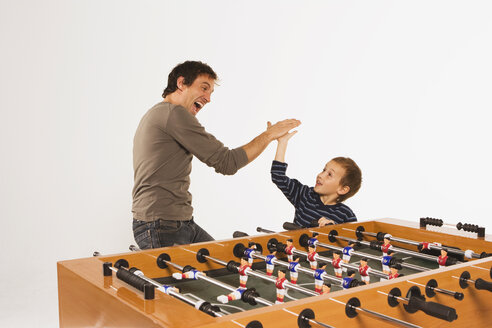 Vater und Sohn (4-5) beim Tischfußball, Hände klatschen - WESTF11005