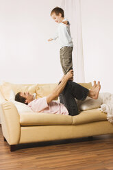 Vater und Sohn (4-5), herumalbern, Junge balanciert auf den Knien des Mannes - WESTF10984