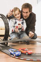Vater und Sohn (4-5) spielen mit einer Spielzeugrennbahn - WESTF10971