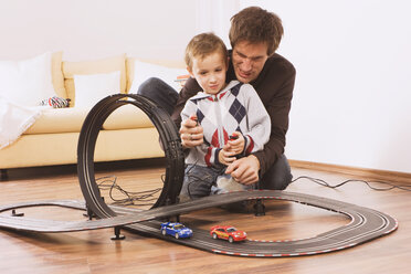 Vater und Sohn (4-5) spielen mit einer Spielzeugrennbahn - WESTF10970