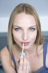 Young woman applying lipstick, portrai - WESTF10844