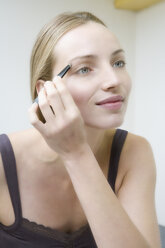 Young woman plucking eyebrows, close up - WESTF10799