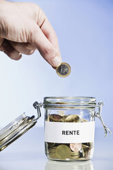 Person putting Euro coin into preserving jar, close up - CLF00681