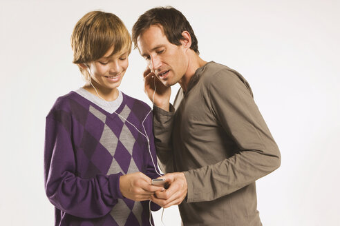 Vater und Sohn (13-14) hören einen MP3-Player - WESTF11019