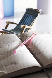 Notebook and pen, deckchair in background, close-up - 10644CS-U