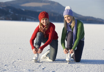 Austria, Salzkammergut, Lake Irrsee, Female teenagers (14-15) tieing skates - WWF00839