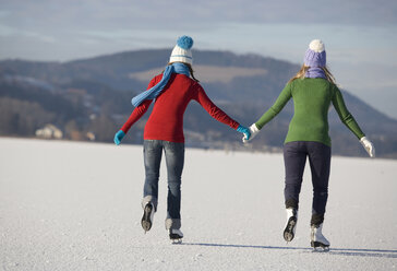 Austria, Salzkammergut, Lake Irrsee, Female teenagers (14-15) skating, rear view - WWF00827